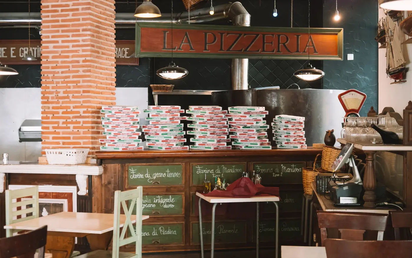 Stacked pizza boxes on the counter of a small pizzeria, ready for pickup and delivery orders